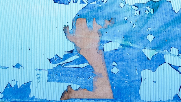 Superficie de plástico irregular y ondulada con restos de película y papel escamosos. Fondo azul obsoleto abstracto. Copie el espacio, diseñe. Fondo o textura de la pared de la pintura azul del grano.