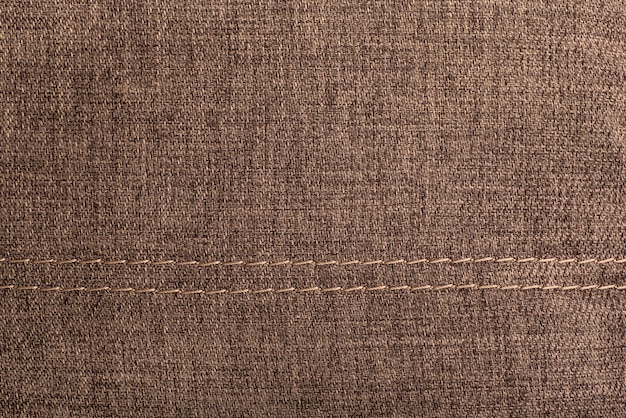 Superficie textil con costuras. Fondo marrón con textura.