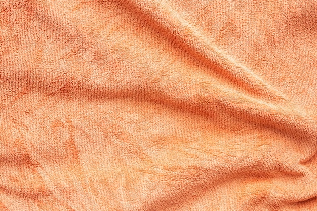 Superficie de textura de tela de toalla naranja cerca de fondo