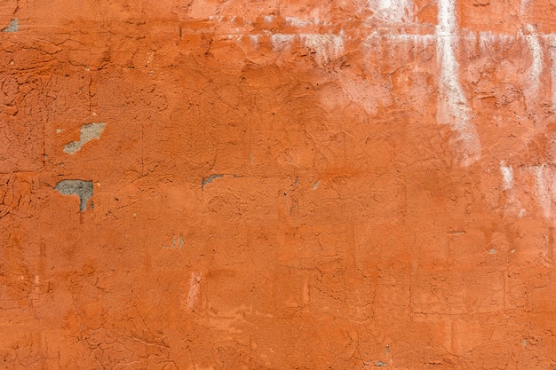 Superfície texturizada de um velho muro de concreto pintado de laranja