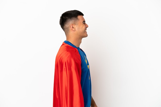 Superheld über isoliertem weißem Hintergrund lachend in Seitenlage