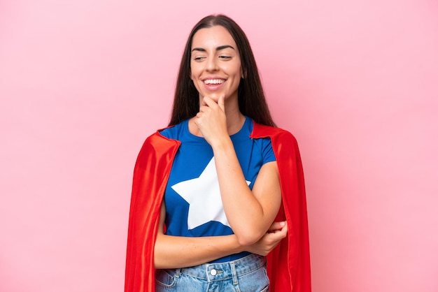 Superhéroe mujer caucásica aislada sobre fondo rosa mirando hacia el lado