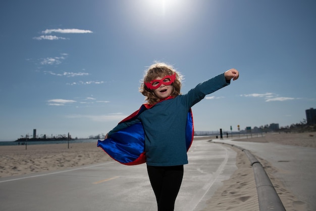 Superhéroe niño en un abrigo de superhéroe rojo concepto de superhéroe