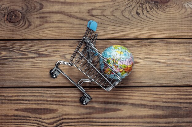 Supermercado global, envío. Carrito de la compra con globo sobre una mesa de madera