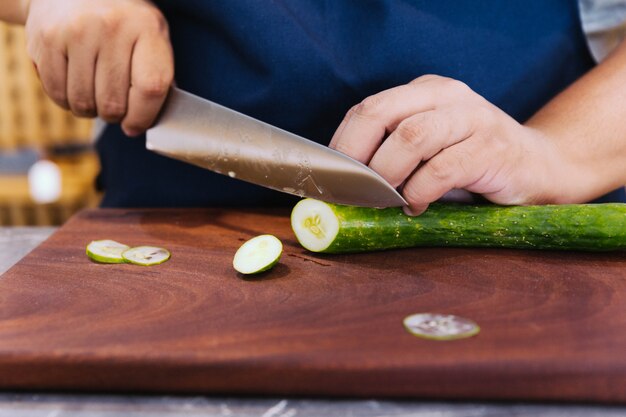 Superscharfes japanisches Küchenmesser schnitt Zucchini in ultradünne Scheibe auf hölzernem Schneidebrett.