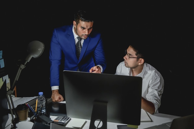 Supervisor asiático del hombre que culpa al personal durante el trabajo del turno de noche