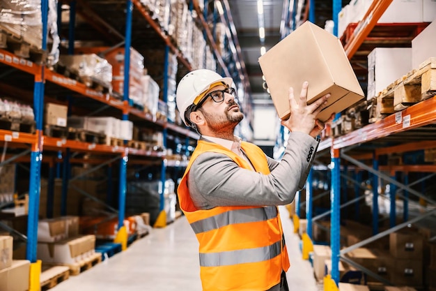 Un supervisor colocando una caja con productos en el estante del almacenamiento