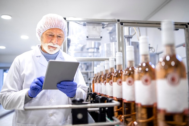 Supervisor experimentado que controla el proceso de producción de vino en una fábrica de embotellado de bebidas alcohólicas