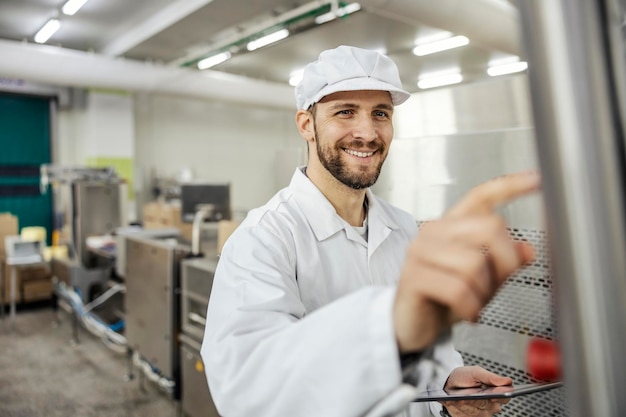 Un supervisor de una fábrica de carne toca la pantalla de una máquina procesadora de carne mientras sostiene una tableta