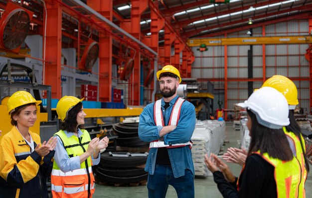 El supervisor y un grupo de trabajadores de la fábrica que llevan cascos de seguridad se reúnen para dar un breve informe.