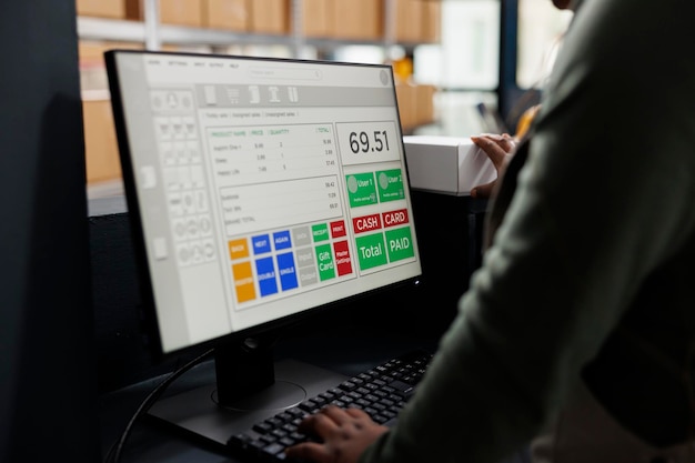 Foto supervisor mirando los detalles de envío de productos en la computadora, trabajando en los pedidos de los clientes preparando paquetes en el mostrador del almacén. empleado afroamericano analizando logística de mercancías.