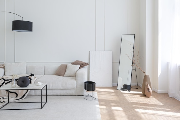Superweißes, schlichtes, sauberes und stilvolles interieur mit modernen möbeln in nude-farben und kontrastierenden schwarzen elementen, luxuriöses design eines großen, hellen wohnzimmers
