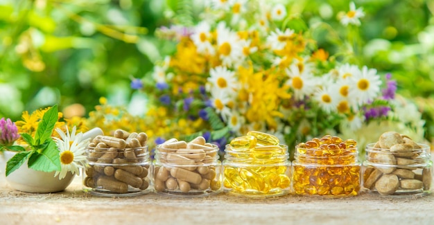 Suplementos e vitaminas em potes de vidro sobre uma mesa de madeira com fundo de flores desfocadas