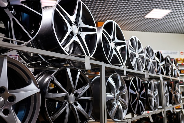 Suporte com rodas de liga leve em loja de pneus moderna, foto de perto de rodas de automóveis em oficina de automóveis