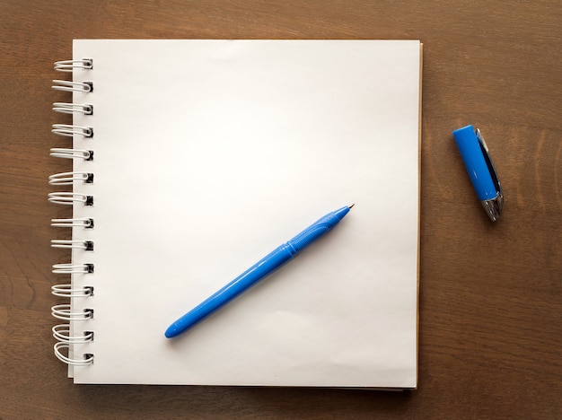 Suporte de caneta azul para bloco de notas em uma mesa de madeira