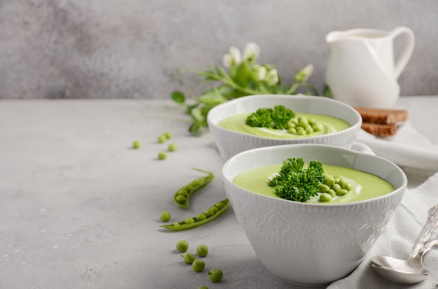 Suppe der grünen Erbse in den Schüsseln auf grauem Beton oder Stein.