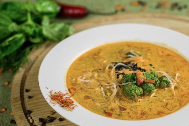 Suppe mit Brokkoli, Reisnudeln und Gemüse auf einem Holzständer