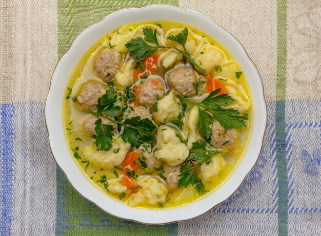 Suppe mit Fleischbällchen und Knödel auf einer Leinenserviette Nahaufnahme oben