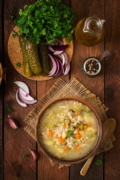 Suppe mit in Essig eingelegten Gurken und Perlgerste - rassolnik auf einem hölzernen Hintergrund. Draufsicht.