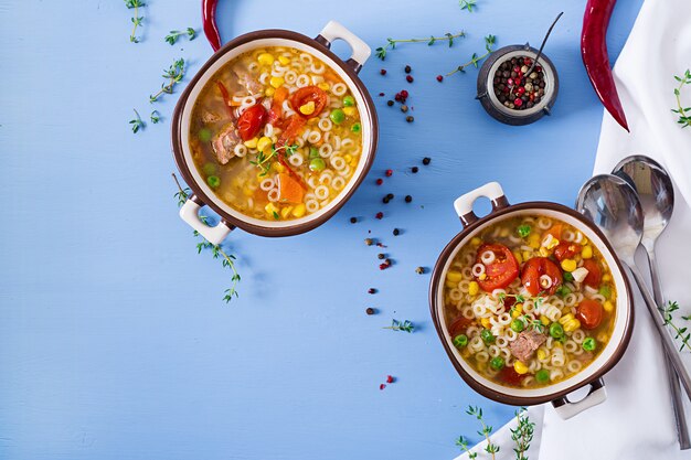 Suppe mit kleinen Teigwaren, Gemüse und Fleischstücken in der Schüssel auf blauer Tabelle. Italienisches Essen.