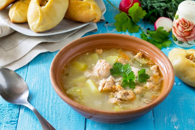 Suppe mit Lachsohren und offenen Kuchen mit rotem Fisch auf dem Küchenholzhintergrund