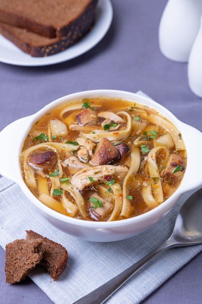 Suppe mit Pilzen, Hühnchen und Nudeln in einem weißen Teller. Traditionelles russisches Gericht. Nahansicht.