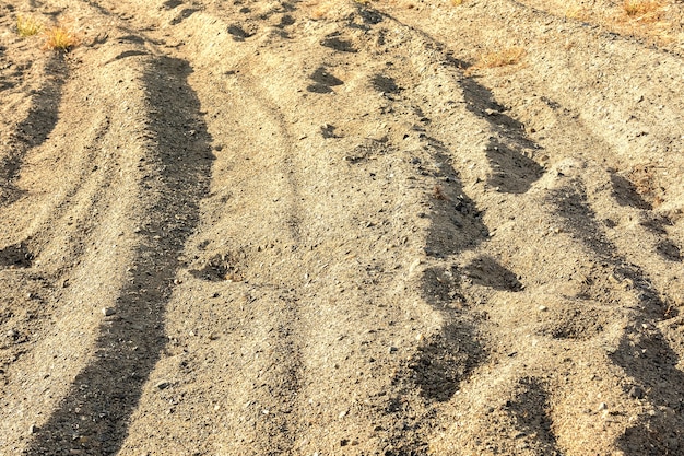 Un surco profundo y huellas en un camino arenoso Patrón y textura de arena