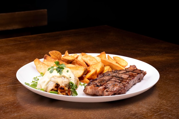 Surf and Turf gebratenes Fischgericht mit gegrilltem Steak und Kartoffeln Vorderansicht auf Holztisch