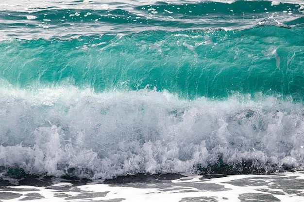 Surf da onda do mar com águas claras na costa com pedras pequenas