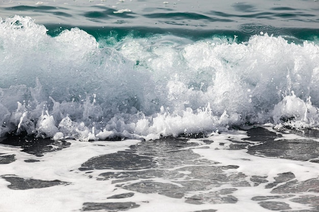 Surf da onda do mar com águas claras na costa com pedras pequenas