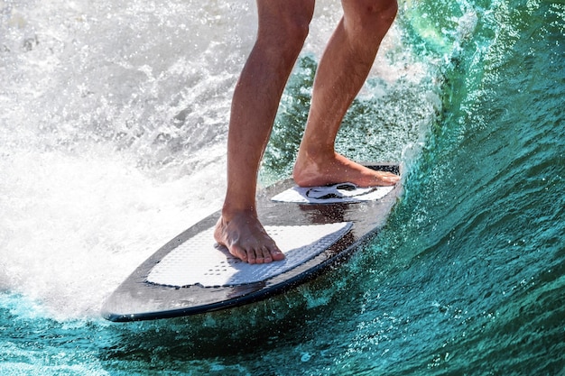 Surfando. Pés de atleta em uma prancha em uma onda