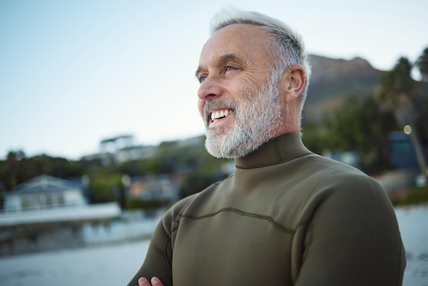 Surfar homem feliz e sênior na praia para paz calma ou liberdade de espírito durante as férias no Rio de Janeiro Brasil Esportes de aposentadoria e idosos relaxam antes de surfar para o bem-estar