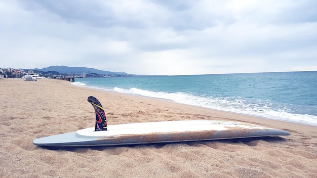 Foto surfbrett am sandstrand gegen bewölkten himmel