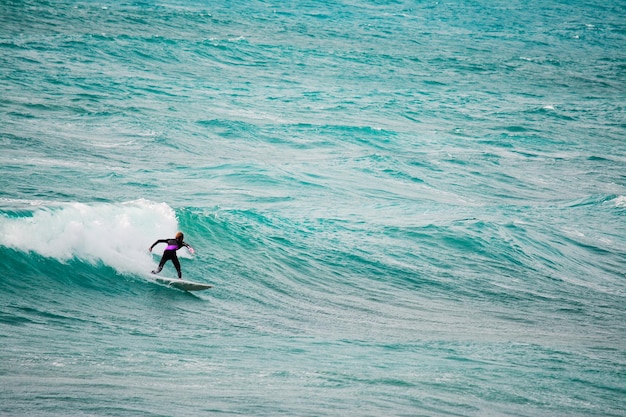 Surfer auf einer Welle im blauen Meer Gedreht in Sardinien Italien