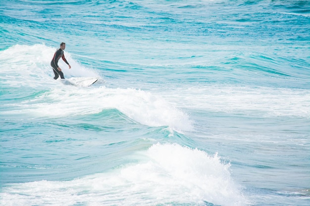 Surfer auf weißen Wellen im türkisfarbenen Meer