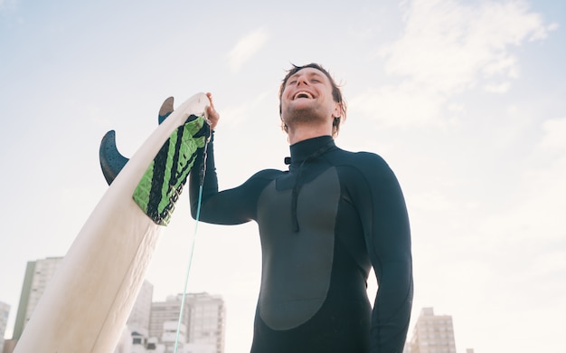 Surfer, der am Strand mit Surfbrett steht