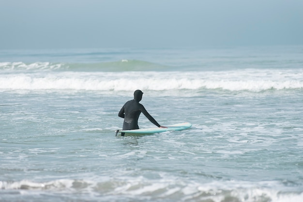 Foto surfer, der am strand spazieren geht