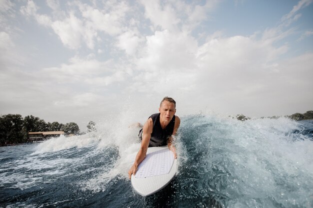 Surfer, der auf einer weißen Tafel liegt und den Fluss hinunter schwimmt