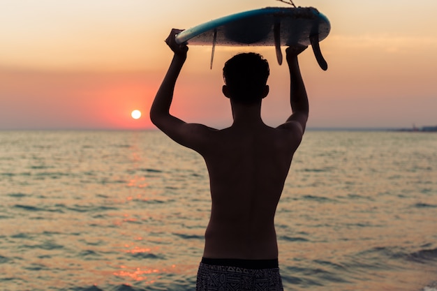 Surfer, der sein Surfbrett hält und nach Wellen sucht