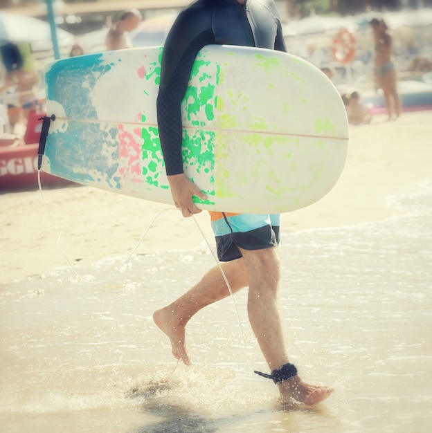 Surfer mit Longboard am Strand