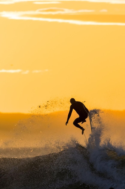 Surfer reiten auf einem Punkt und brechen Wellen und werden bei Sonnenuntergang in Jeffreys Bay, Südafrika, ausgelöscht