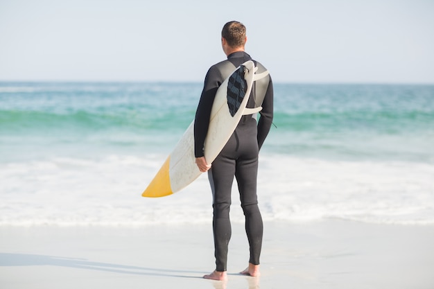 Surfer stehen am Strand mit einem Surfbrett