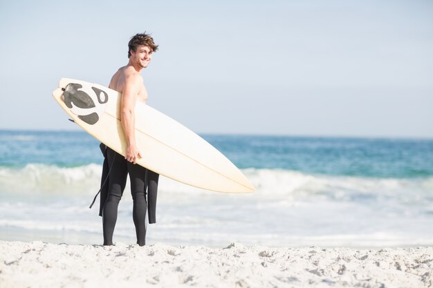 Surfer zu Fuß am Strand mit einem Surfbrett