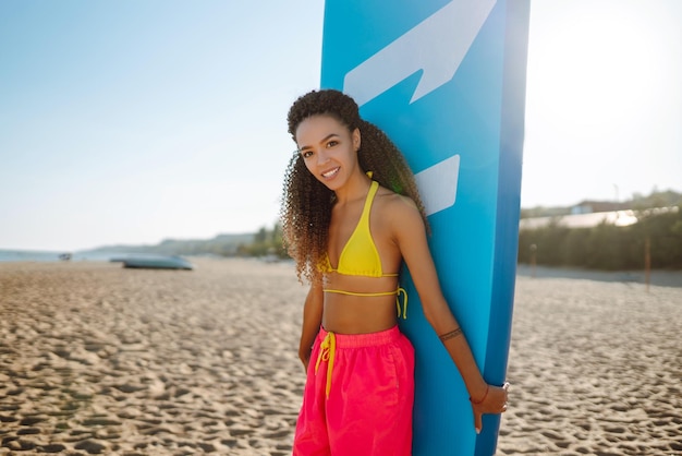 Foto surferin geht mit einem brett am sandstrand extremsport reisen wochenend-lifestyle