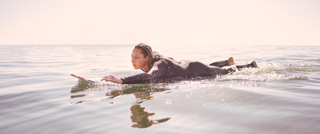 Foto surferin und schwimmen in wellen meer und ozean für sommerabenteuer freiheit und himmelsmockup weibliches surfen an bord im wasserstrand und entspannung für tropische ferien, naturreisen und friedenssport