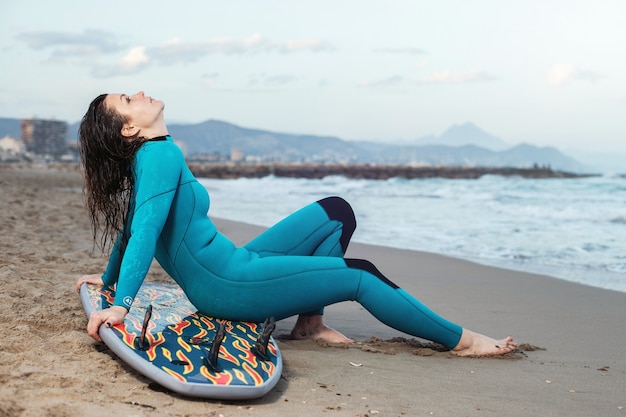 Foto surfermädchen, das mit brett am sandigen strand geht. surfer weiblich. schöne junge frau am strand. wassersport. gesunder aktiver lebensstil. sommerurlaub. extremsport.