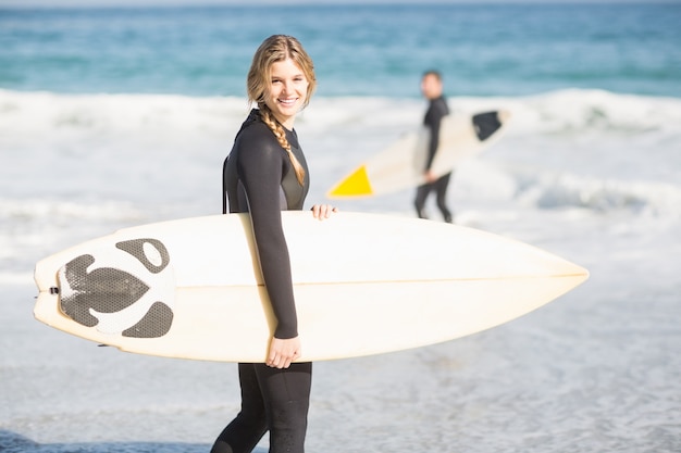 Surfista caminando por la playa con una tabla de surf