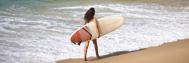 Surfista caminhando com uma prancha de surf na praia tropical