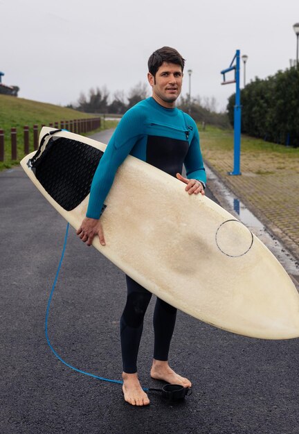 Foto surfista de fato de mergulho com prancha no caminho costeiro