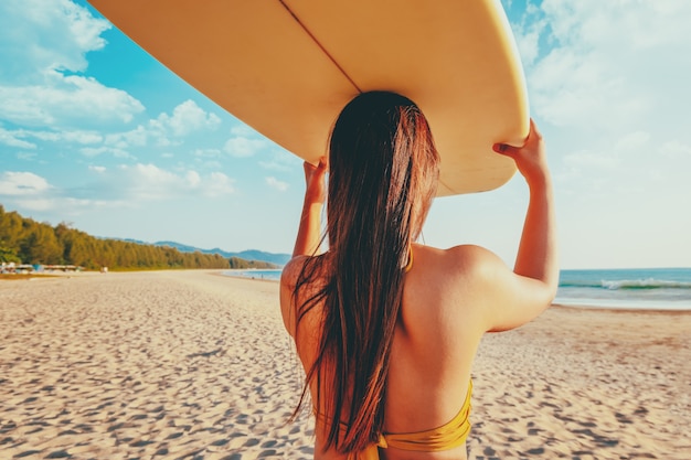 Surfista de mulheres com prancha de surf na praia